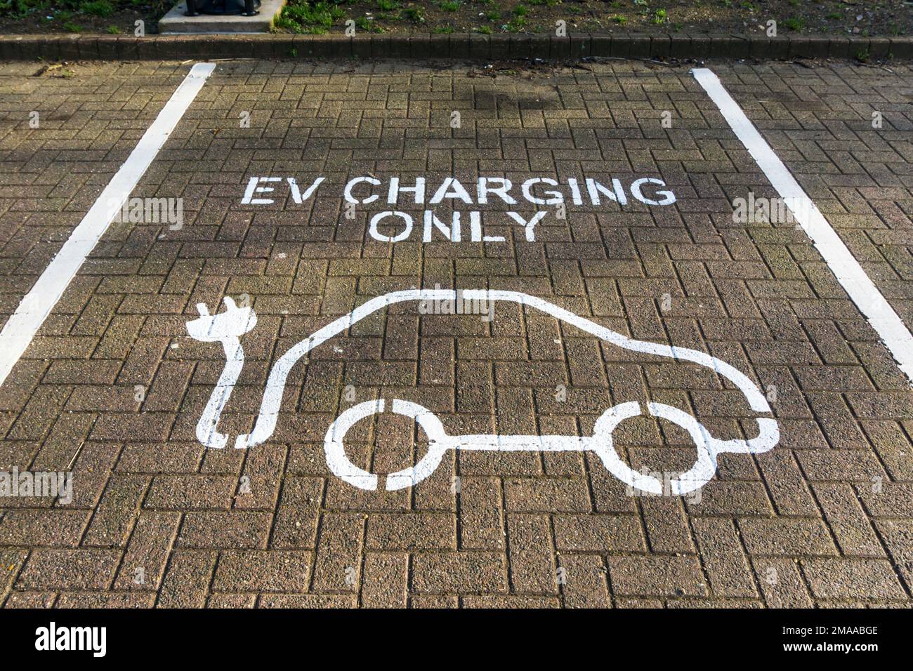 Sign painted on road in car park reads EV Charging Only. Stock Photo