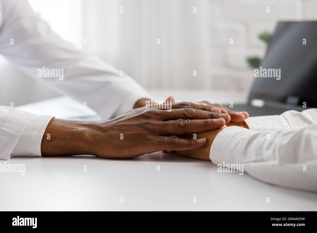 An African American doctor comforts a woman at a reception in his office. Medical support. The doctor's consultation. Help the patient. Stock Photo