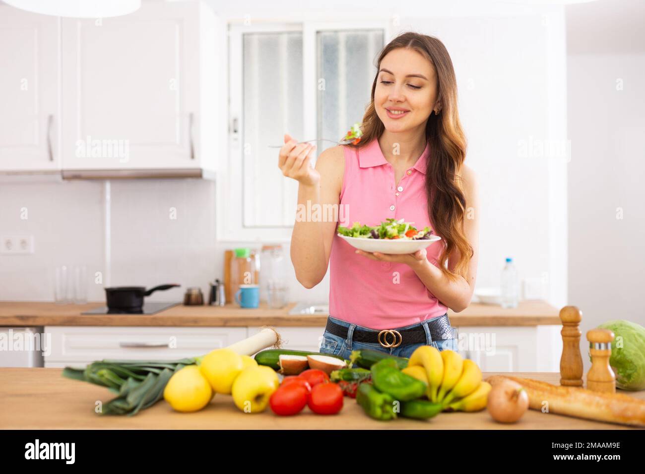 Smiling young woman enjoying salad at home Stock Photo