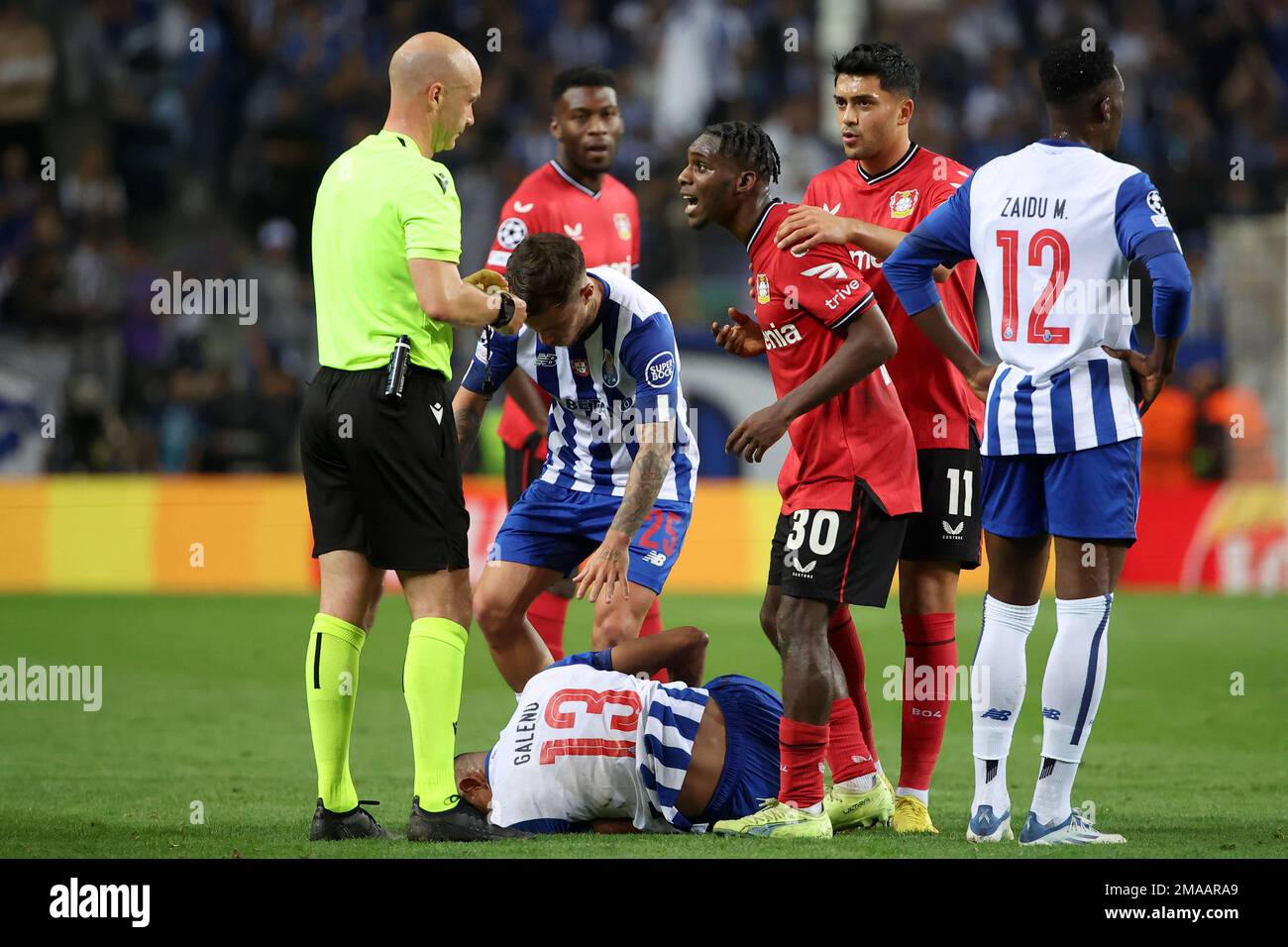 Leverkusen's Jeremie Frimpong, center, reacts as Referee Anthony Taylor