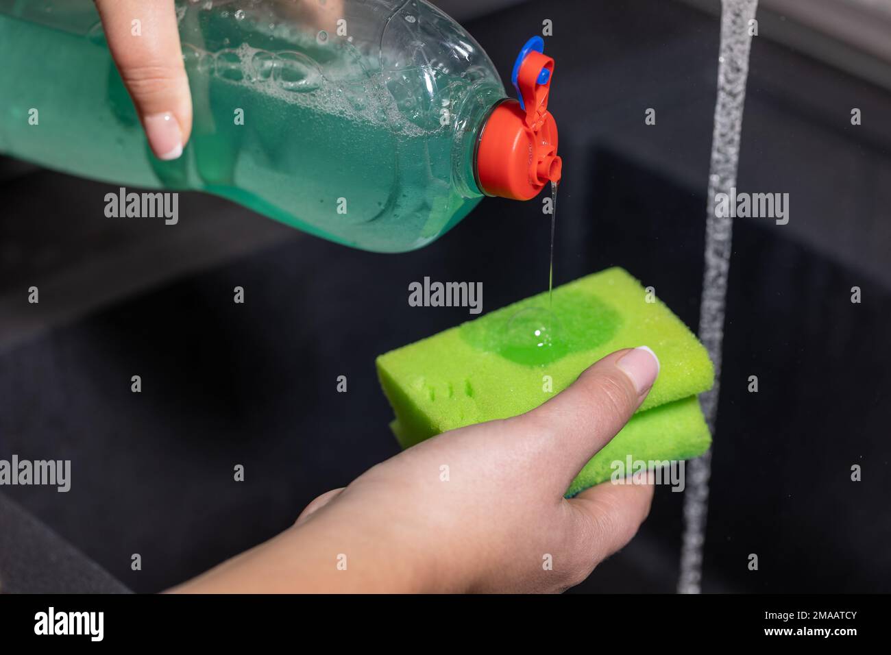 Woman uses dishwashing detergent for wash up dishes in the kitchen at