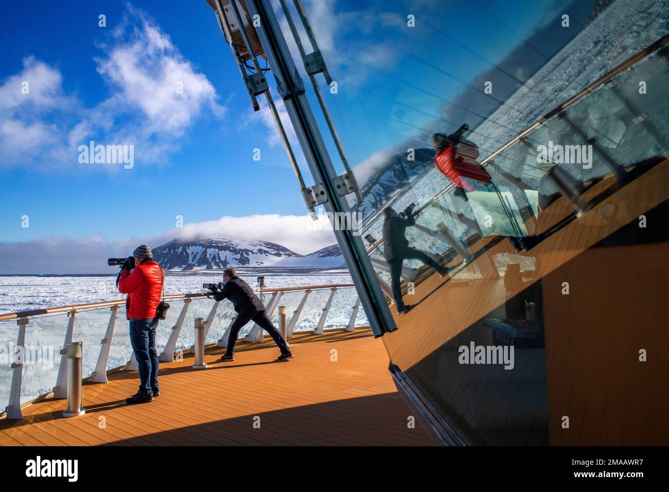 Tourist taken pictures in the main deck of the expedition cruise vessel Greg Mortimer in Svalbard archipelago, Arctic Norway. Stock Photo