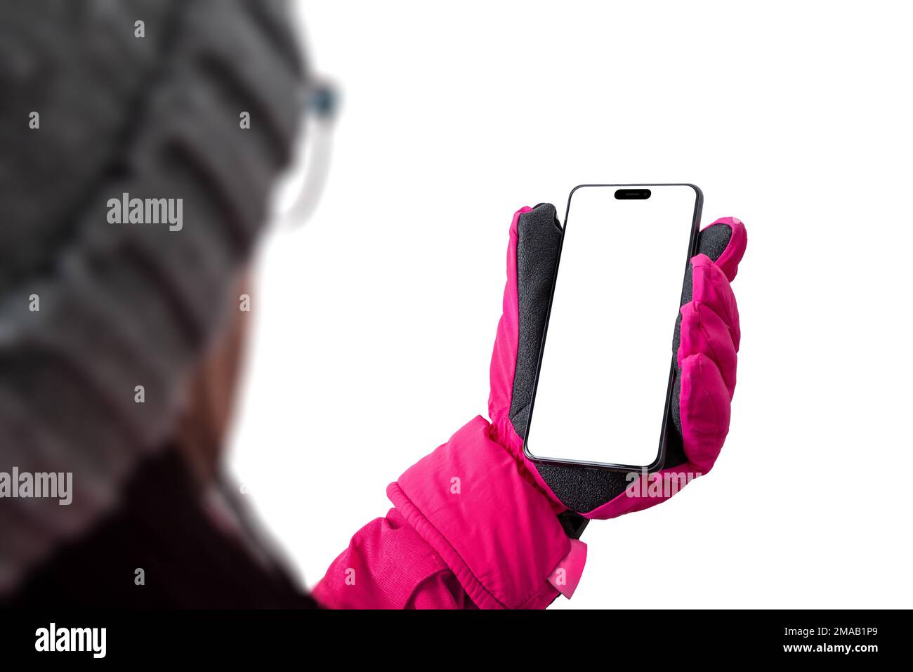 Girl holds a mobile phone in ski gear.. Pink winter jacket with gloves and hat. Concept of using a phone on a ski slope; Isolated display and backgrou Stock Photo