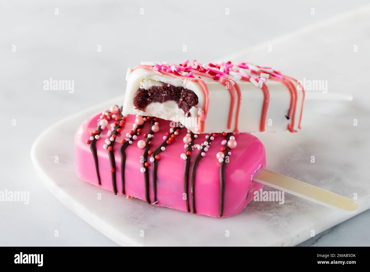Valentine's Day cakesicles on a marble slab with a bite out of the one