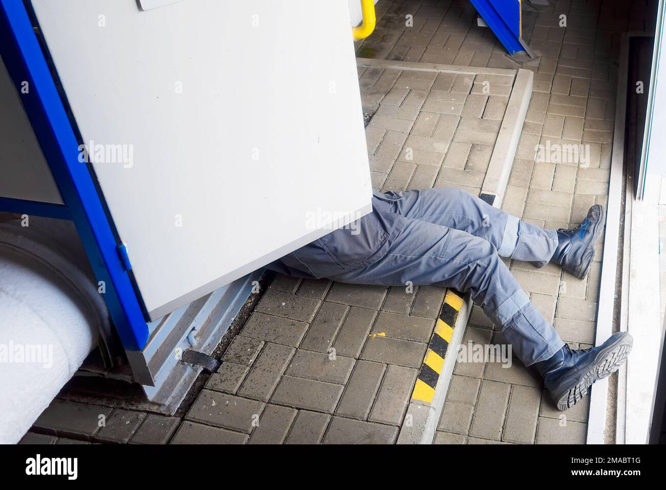 Accident. Electric shock to person. Out of electric panel stick out legs of worker. Electrician is electrocuted and lies on floor at production site. Compliance with labor protection.. Stock Photo