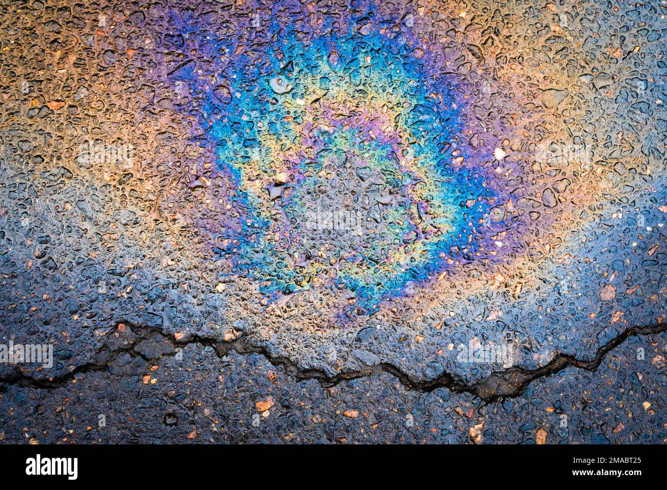 Multi colored oil spill on asphalt road. The concept of environmental ...