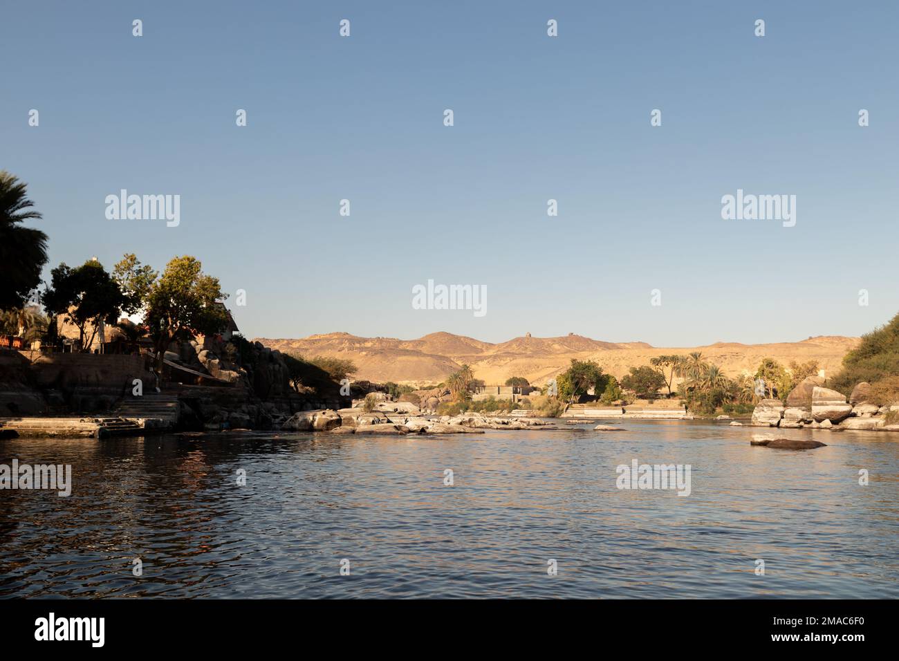 Egypt landscape with sand dunes, vegetation and rocky river bank view from a boat under blue sky Stock Photo