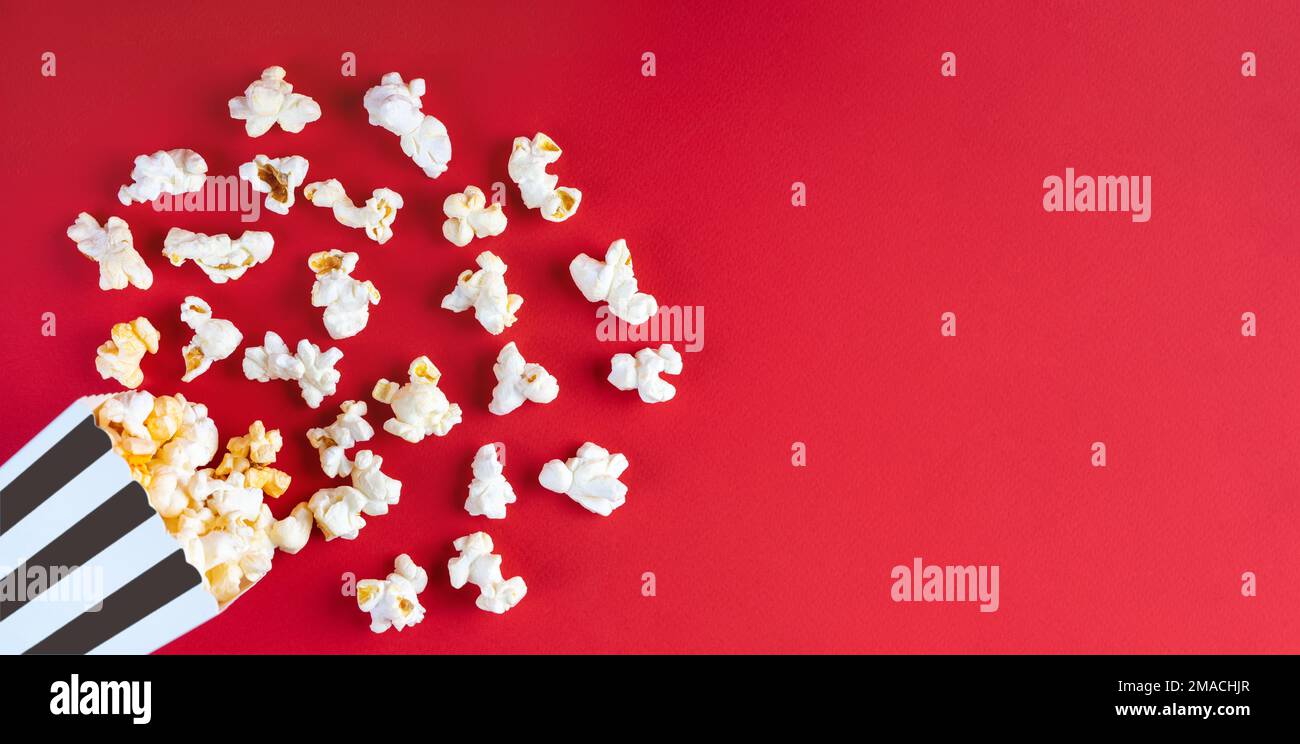 Tasty cheese popcorn falling out of a black striped carton bucket ...