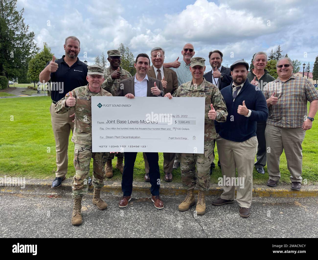 Joint Base Lewis-McChord Service members and civilians and representatives from Puget Sound Energy seen giving a thumbs up to the completion of the Decentralization project and the rebate check of over $1.5 million May 25. Stock Photo