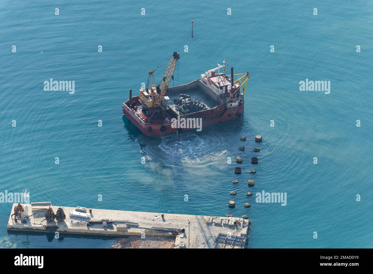 A boat is dredging the sea. Dredging is the removal of sediments and debris from the bottom of lakes, rivers, harbors, and other water bodies. Stock Photo