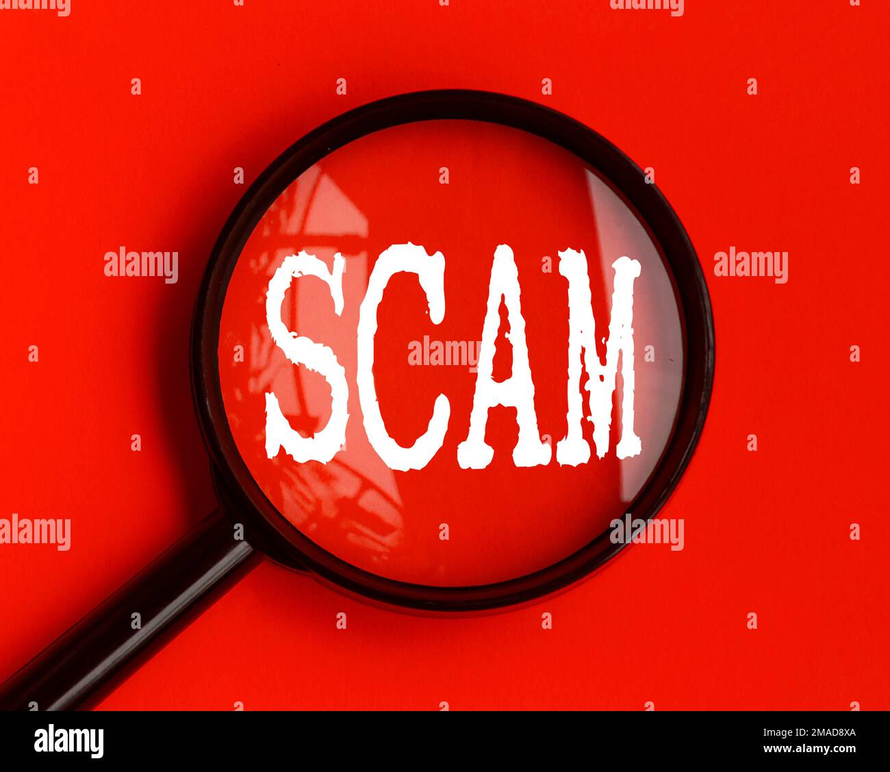 Scam text on red cover with magnifying glass. Scamming and fraud