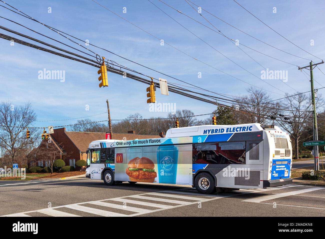 MATTHEWS, NC, USA-15 JANUARY 2023: Hybrid Electric city bus on Trade Street. Sunny, blue sky day. Stock Photo