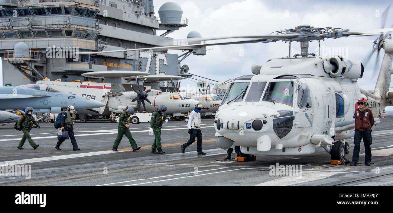 220526-N-BR419-1108 PHILIPPINE SEA (May 26, 2022) Sailors attached to the Japan Maritime Self-Defense Force (JMSDF) destroyer JS Teruzuki (DD 116) board an SH-60K Seahawk on the flight deck of the U.S. Navy’s only forward-deployed aircraft carrier USS Ronald Reagan (CVN 76). The U.S. Navy and JMSDF routinely conduct naval exercises together, strengthening the U.S.-Japan alliance and maintaining a free and open Indo-Pacific region. Ronald Reagan, the flagship of Carrier Strike Group 5, provides a combat-ready force that protects and defends the United States, and supports alliances, partnership Stock Photo