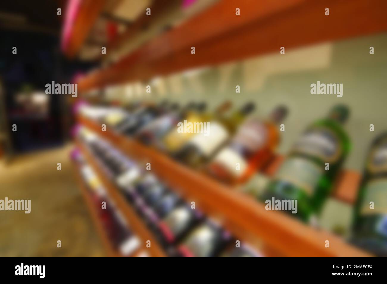 Blurred liquor store aisle wine rack whisky champagne bottles lying on