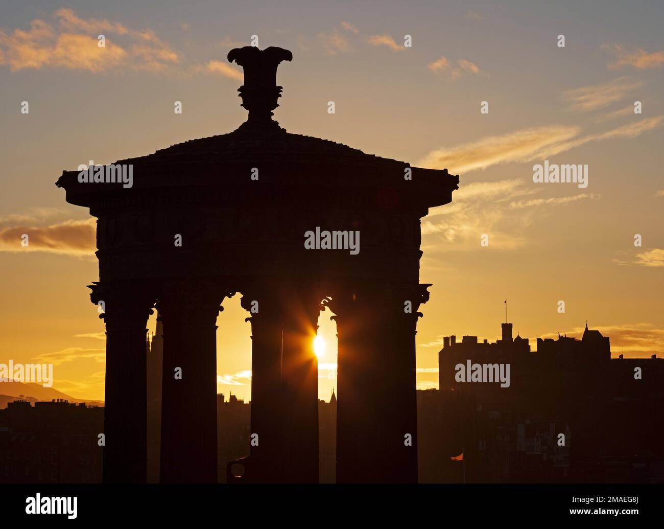 Calton Hill and Edinburgh city centre, Scotland, UK. 19th January 2023. Twinkling cool sunset at 4 degrees centigrade, pictured through the historic architecture of the Dugald Stewart monument and Edinburgh Castle in the background. Credit: Archwhite/alamy live news. Stock Photo