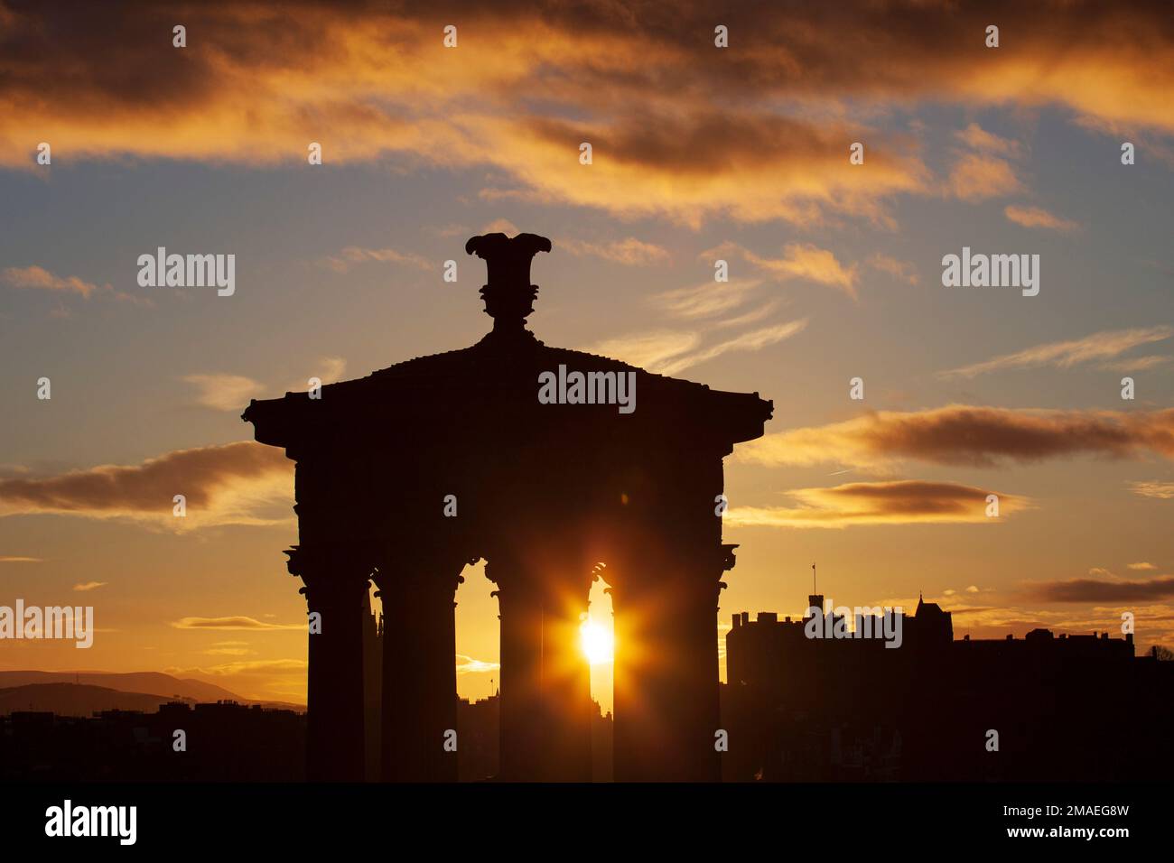 Calton Hill and Edinburgh city centre, Scotland, UK. 19th January 2023. Twinkling cool sunset at 4 degrees centigrade, pictured through the historic architecture of the Dugald Stewart monument and Edinburgh Castle in the background. Credit: Archwhite/alamy live news. Stock Photo