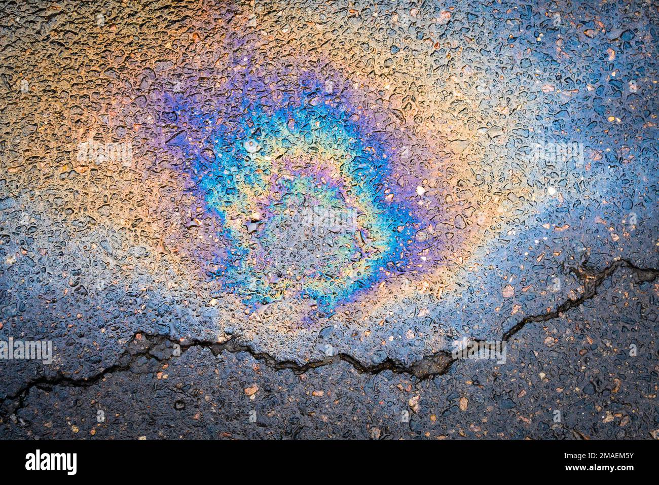 Multi colored oil spill on asphalt road. The concept of environmental