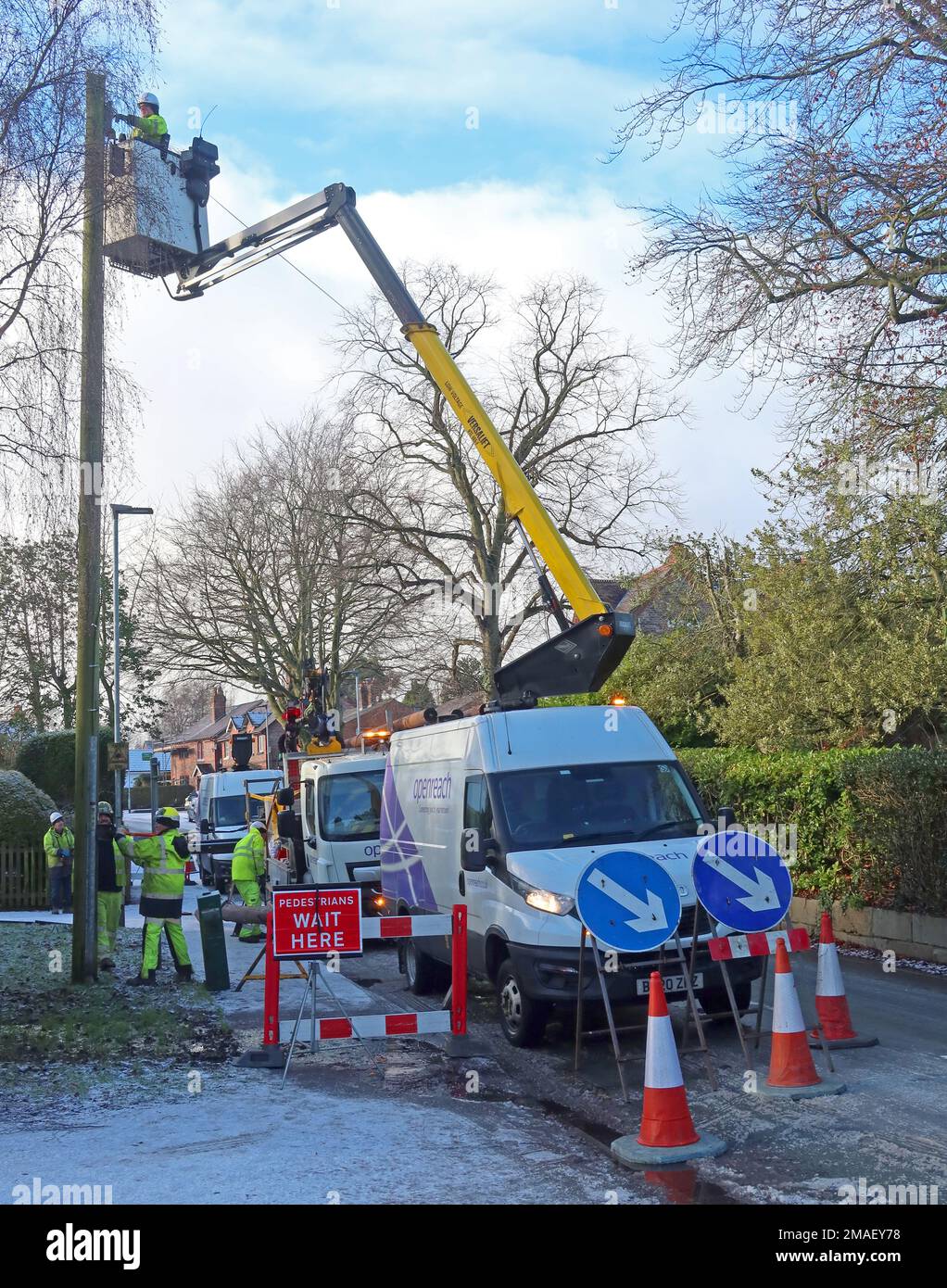 Openreach Telecom engineers, working on domestic phone line / broadband internet copper wire, up a telephone / telegraph pole rural village Stock Photo