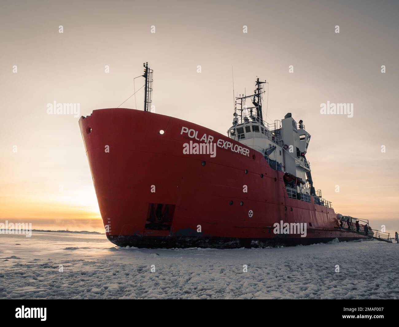 People getting on ice breaker during sunset in the arctic. Stock Photo
