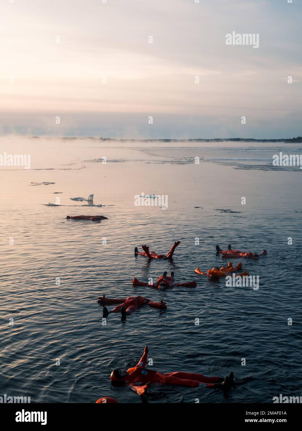 People in arctic survival suits ice floating in the ocean Stock Photo