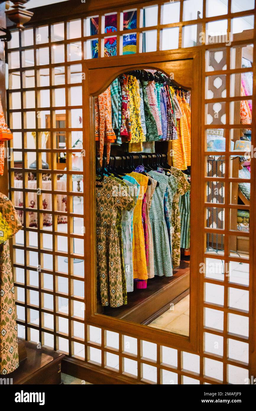 The reflection of traditional colorful dresses sold at a Balinese batik shop on the tall dressing mirror. Stock Photo
