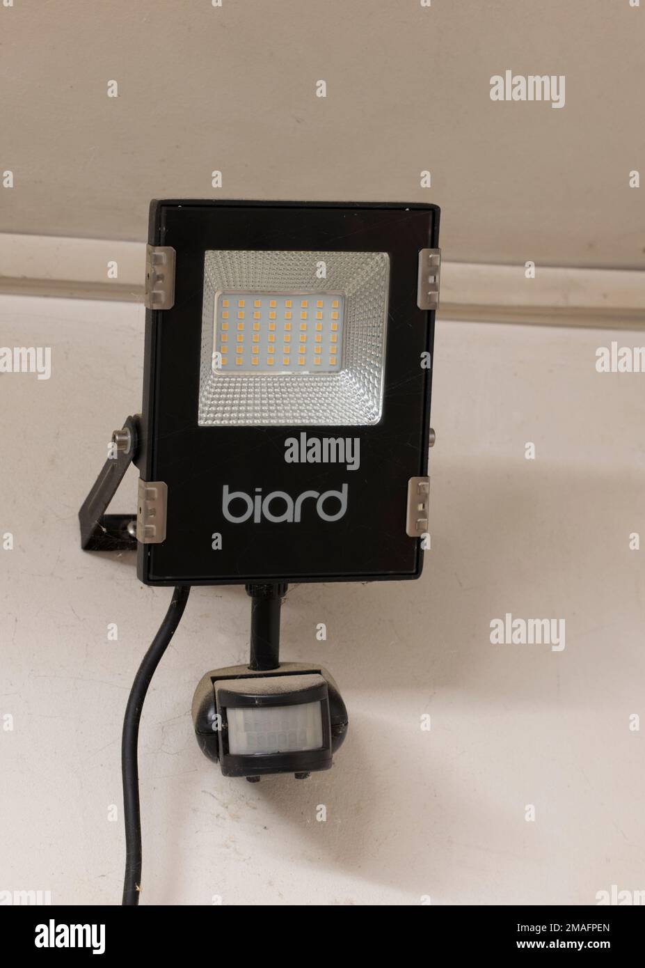 LED 10w outdoor floodlight with sensor mounted on garage wall UK Stock Photo