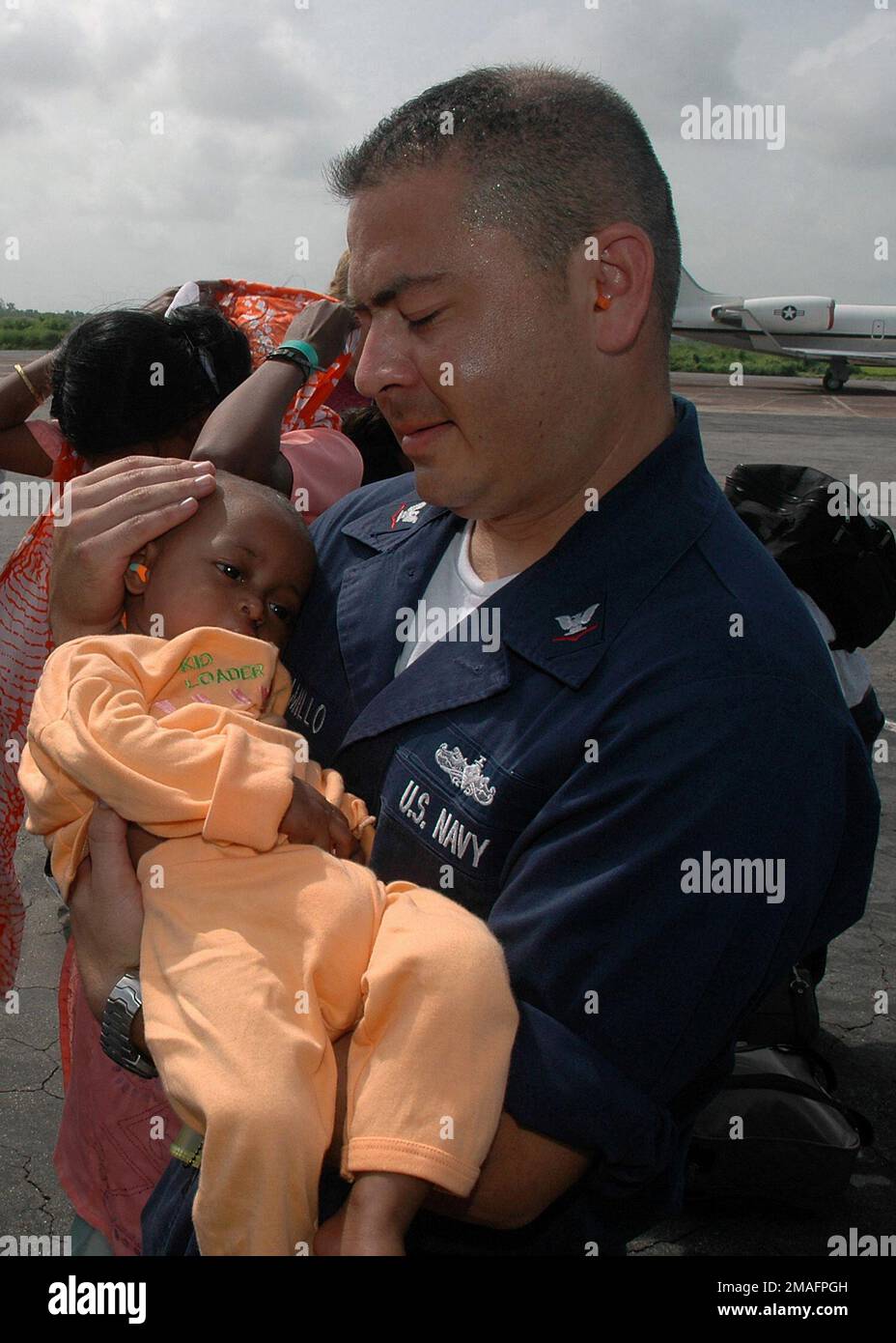 060705-N-3931M-013. [Complete] Scene Caption: US Navy (USN) Hospital Corpsman Third Class (HM3) Javier Jamamillo from the Medical Treatment Facility (MTF), USN Military Sealift Command (MSC) USNS MERCY (T-AH 19), comforts a child that underwent treatment aboard the MERCY at Chittagong Airport, Bangladesh (BGD), during the ship's humanitarian and civic assistance in the country. The MERCY is on a scheduled five-month deployment in Southeast Asia. Its mission is being carried out in close coordination and partnership with local medical care professionals and civilian volunteers from Project HOPE Stock Photo