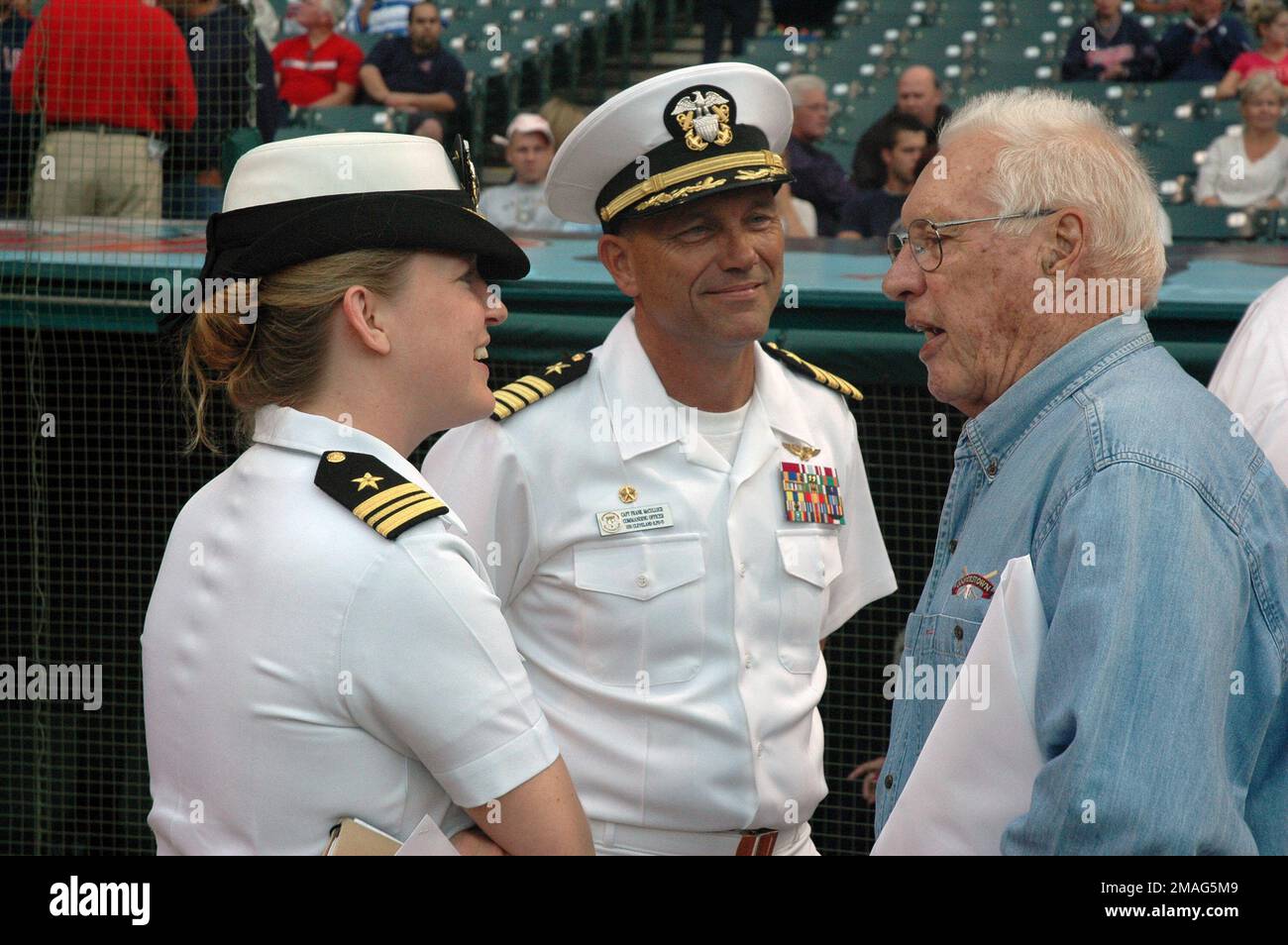 060830-N-1805P-004. [Complete] Scene Caption: U.S. Navy CAPT. Frank McCulloch, center, Commanding Officer of the Austin Class Amphibious Transport Dock USS CLEVELAND (LPD 7), and LT. CMDR. Elizabeth Zimmermann, left, talk to Bob Feller, Major League Baseball Hall of Fame Inductee and World War II Navy veteran, before the start of the Cleveland Indians and Toronto Blue Jays baseball game at Jacobs Field during Navy Week festivities at Cleveland, Ohio, on Aug. 30, 2006. The Cleveland Navy Week, which runs from Aug. 28-Sept. 4, 2006, features Navy participation in community events ranging from pr Stock Photo