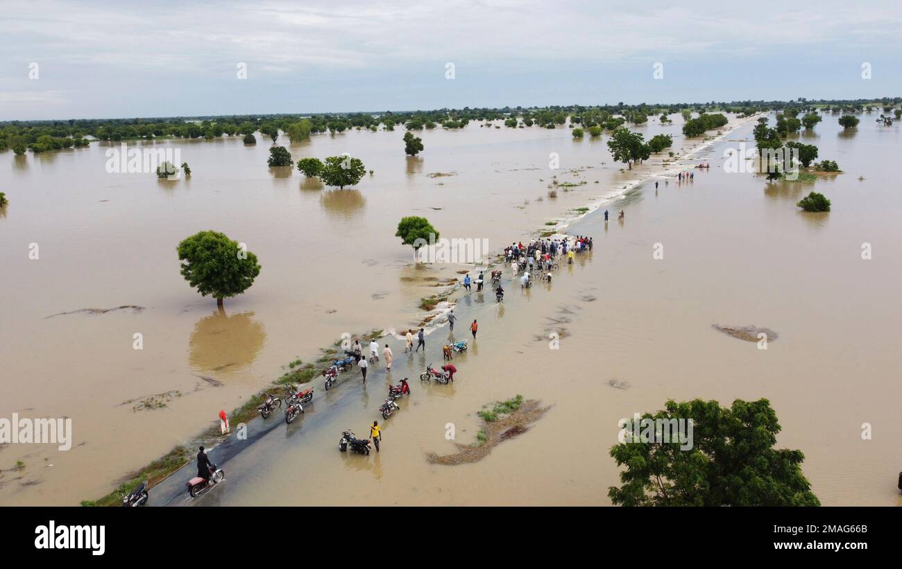Peole walk through floodwaters after heavy rainfall in Hadeja, Nigeria, Monday, Sept 19, 2022. Nigeria is battling its worst floods in a decade with more than 300 people killed in 2021 including at least 20 this week, authorities told the Associated Press on Monday. (AP Photo) Stock Photo