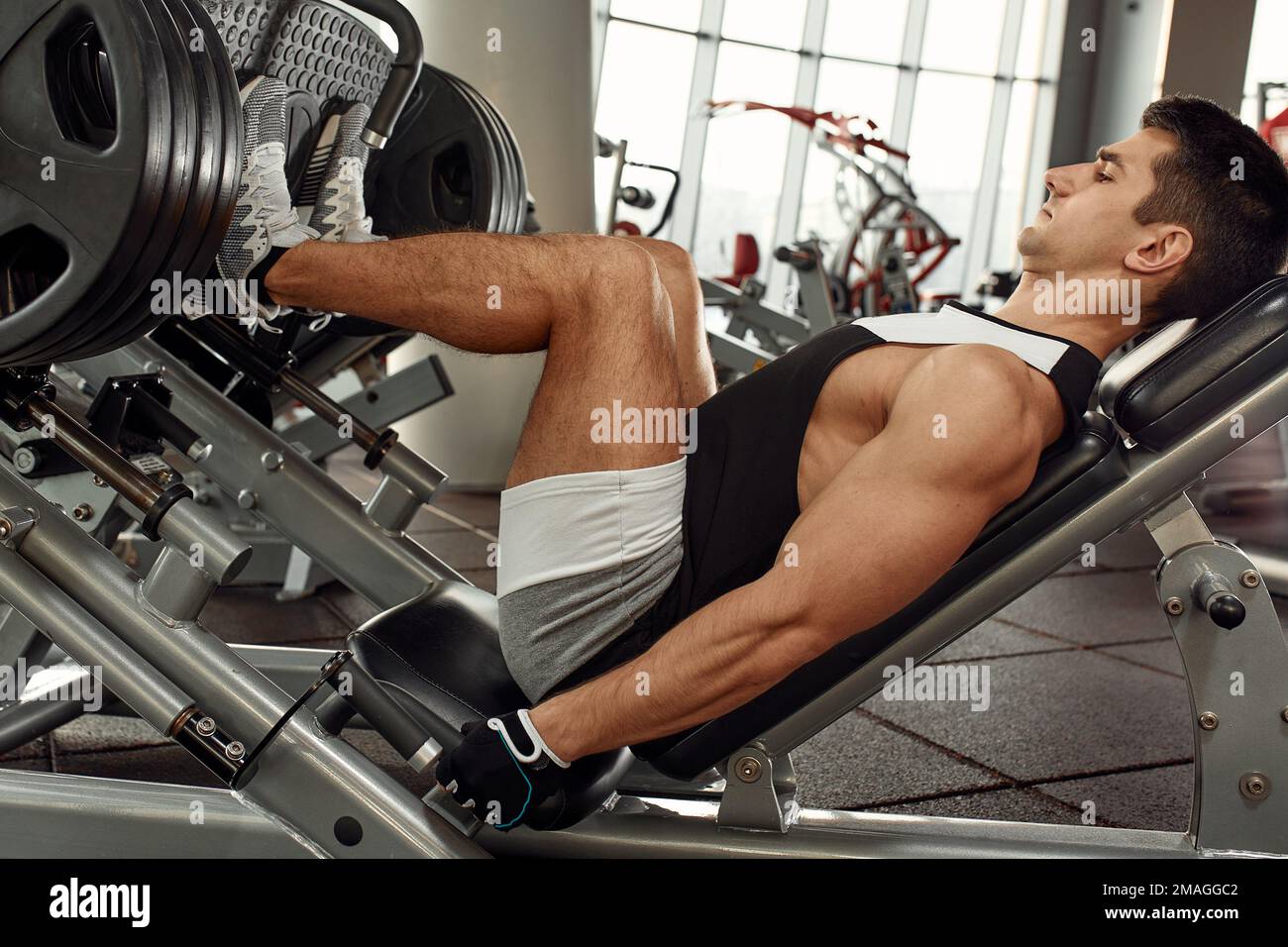 Man Using A Press Machine In A Fitness Club. Strong man doing an exercise on its feet in the simulator. Side view Stock Photo Alamy