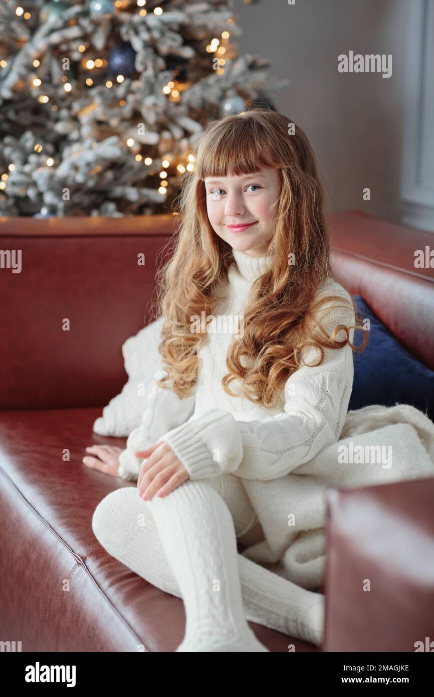 Happy young girl sitting on the sofa by the Christmas tree Stock Photo ...