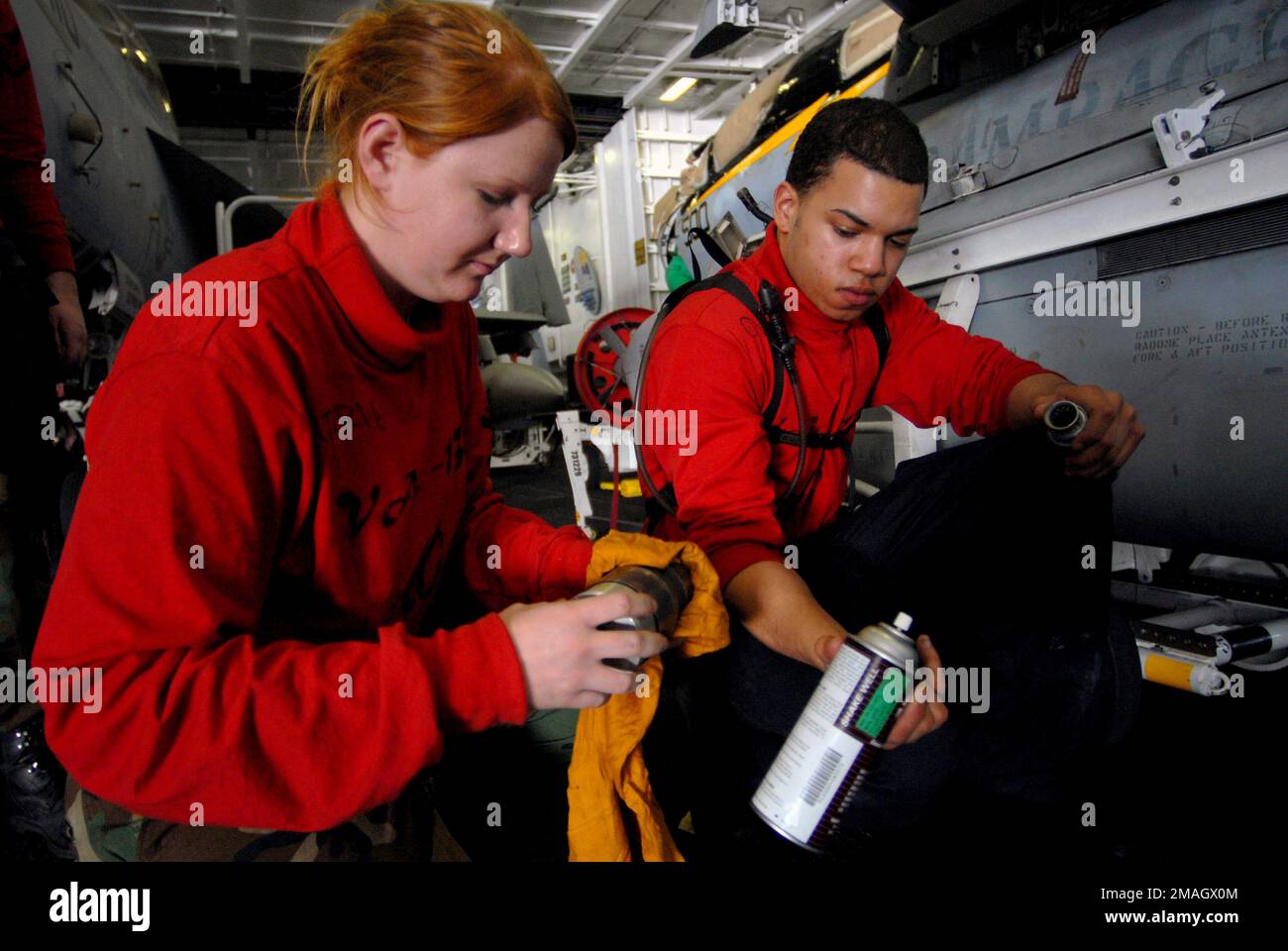 070128-N-2659P-121. [Complete] Scene Caption: U.S. Navy Aviation Ordnanceman AIRMAN Juan Ovales (right) hands tools to Aviation Ordnanceman 3rd Class Katherine Gutherie (left) as they perform maintenance on a bomb rack injection foot, for a a Tactical Electronic Warfare Squadron 138 (VAQ-138,'Yellowjackets') EA-6B Prowler electronic warfare aircraft, in the hangar bay aboard the Nimitz Class Aircraft Carrier USS JOHN C. STENNIS (CVN 74) on Jan. 28, 2007, while the STENNIS and Carrier Air Wing 9 (CVW-9) are conducting carrier qualifications of the coast of Southern California prior to transitin Stock Photo