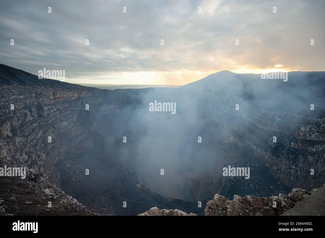 Deep crater hole in earth land with smoke go up. Steam from Masaya crater volcano Stock Photo