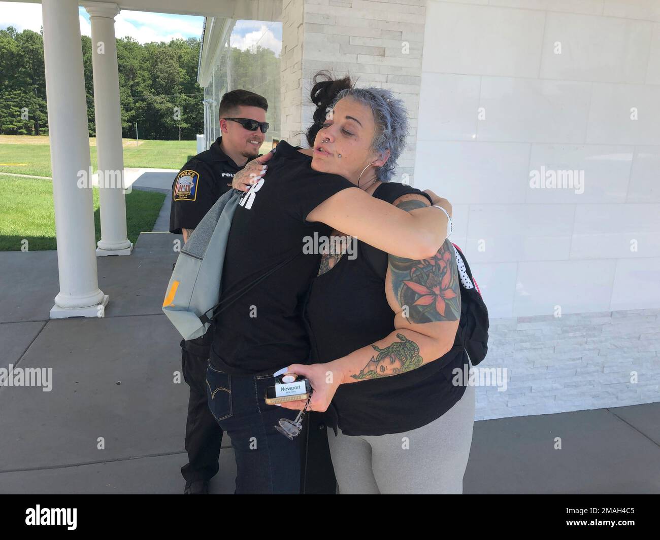 Chesterfield Patrol Officer Travis Adams, left, and peer recovery specialist Joy Bogese, center, hugs Rhonda Kanary while on patrol as part of Project Recover, in Chesterfield County, Va., Monday Aug., 29, 2022. Project Recover is a program that embeds recovering addicts with police and ambulance crews in central Virginia to respond to overdose calls and to go on patrol to reach out to people struggling with drug addiction to try to get them into treatment programs. (AP Photo/Denise Lavoie) Stock Photo