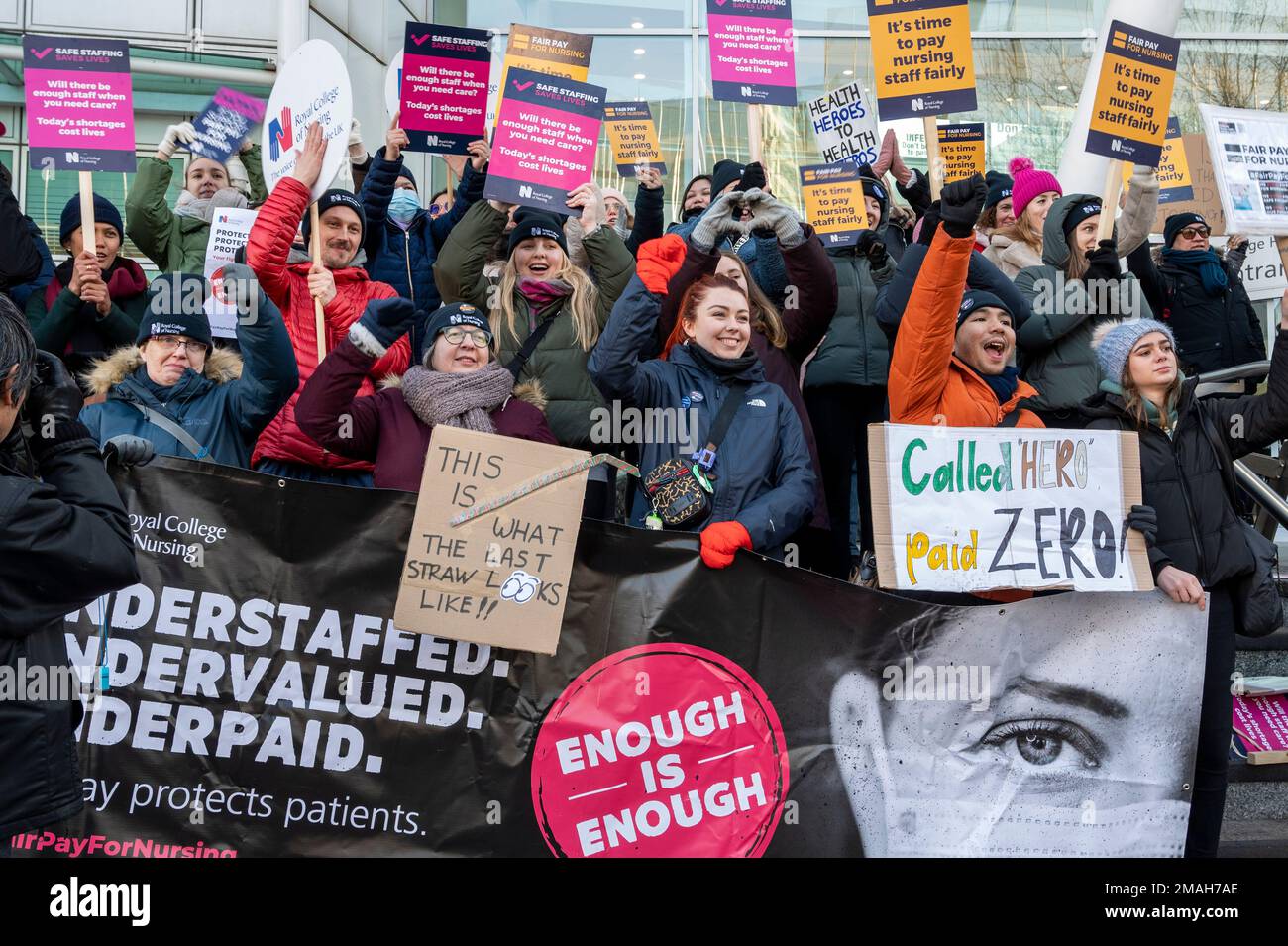 Nurses outside UCH Hospital, London striking for more pay and staff with placards "Called Hero, paid Zero", "This is what the last straw looks like". Stock Photo