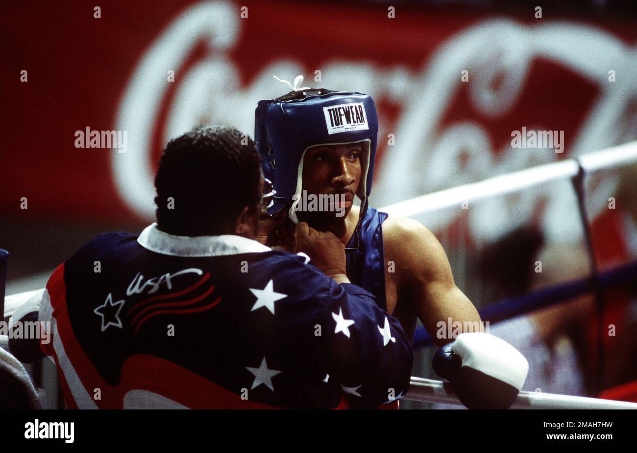 Boxing Coach Tom Mustin fastens the head protector on Air Force Boxer,  STAFF SGT. Ron Simms, prior to his second middleweight match against Marcus  Thomas of Barbados at the Pan Am boxing