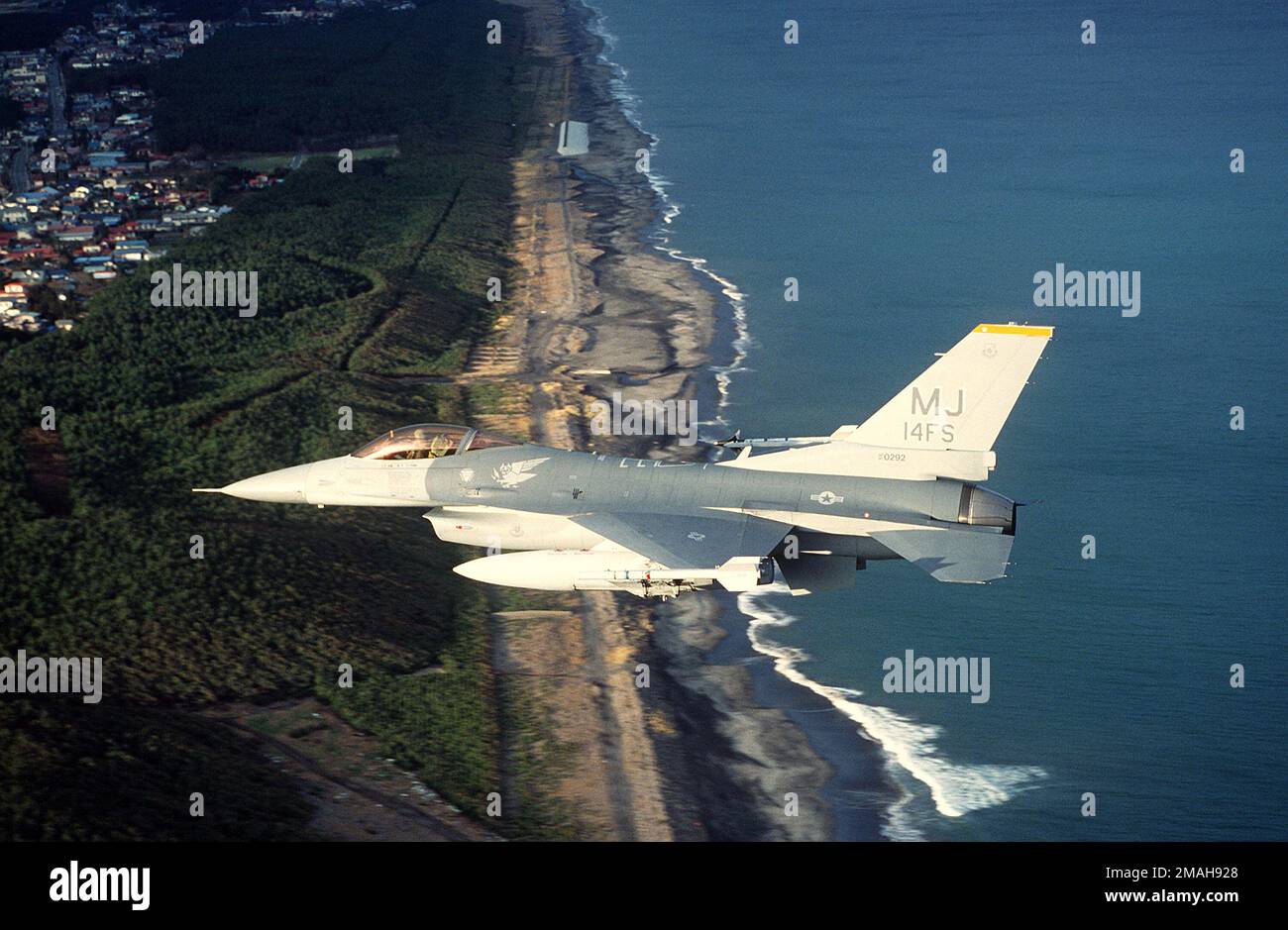 An F-16C Fighting Falcon aircraft of the 14th Fighter Squadron flies over the coastline near Misawa Air Base. The aircraft is armed with AIM-9 Sidewinder missiles.. Country: Japan(JPN) Stock Photo