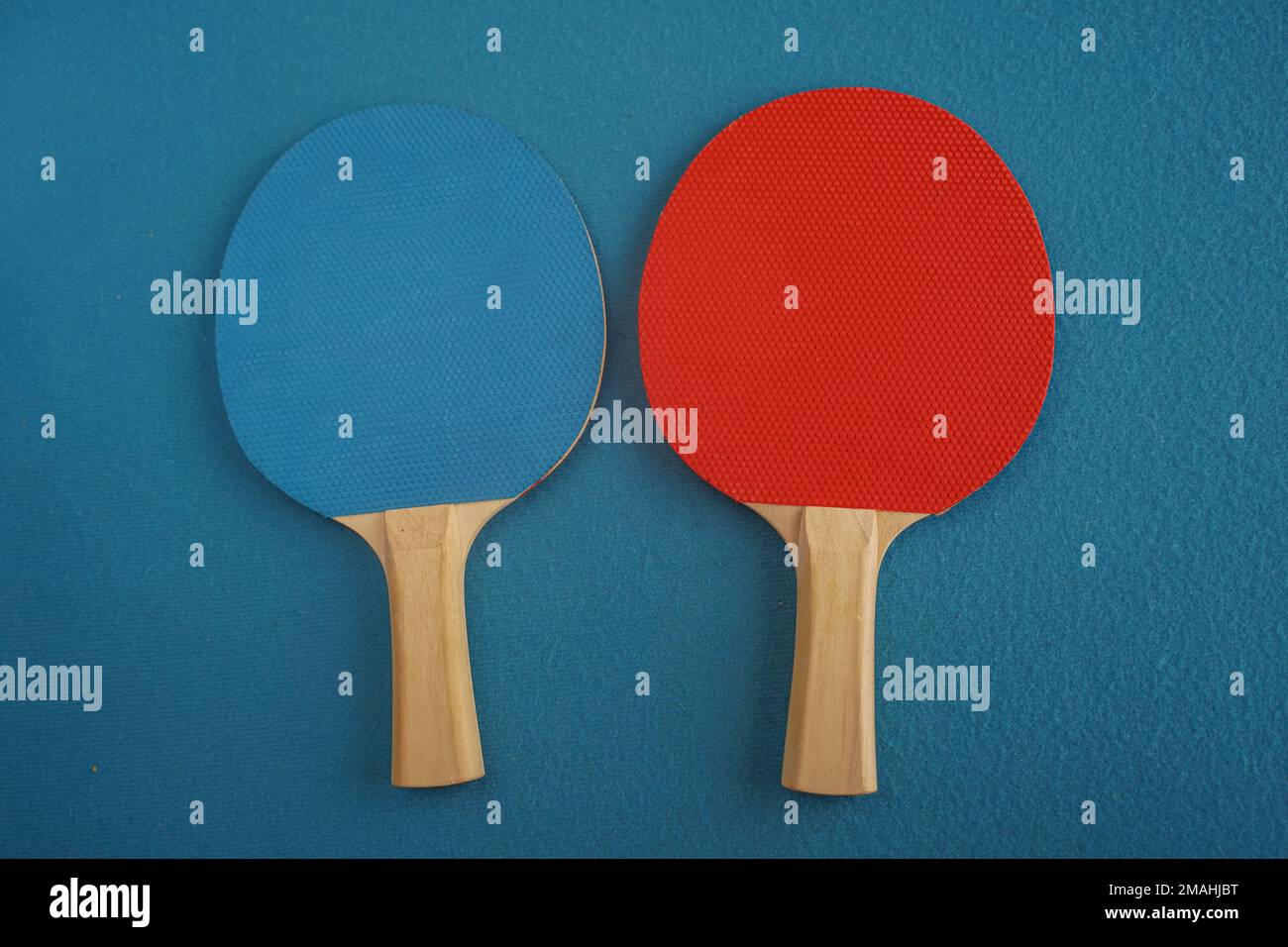 Red and blue table tennis or ping pong rackets lie on a blue background