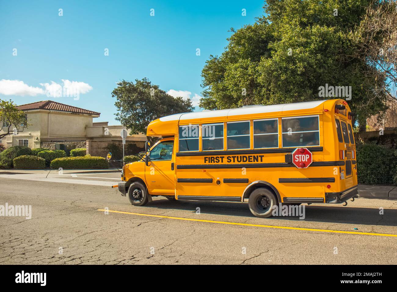Yellow school bus driving along the street in small town in California
