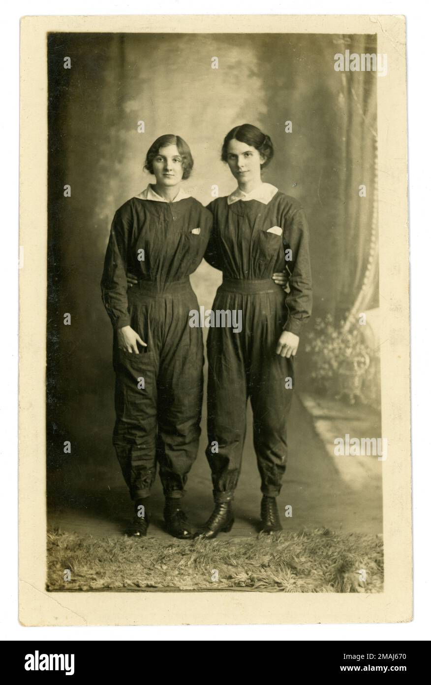 Original WW1 era portrait of 2 young emancipated women proudly  wearing boiler suits, showing comradeship of women working in the munitions industry. The girls are thought to be munitions workers as they are wearing boiler suits - it was a dangerous job where skirts might catch in machinery or knock over dangerous chemicals. The town of Wakefield sent girls to work at the National Filling Factory No. 1, at nearby Barnbow. Women working at this large munitions factory were known as 'Barnbow lasses'. The portrait was taken at Barnes' Black & White Studios, Kirkgate, Wakefield, circa 1916. U.K. Stock Photo