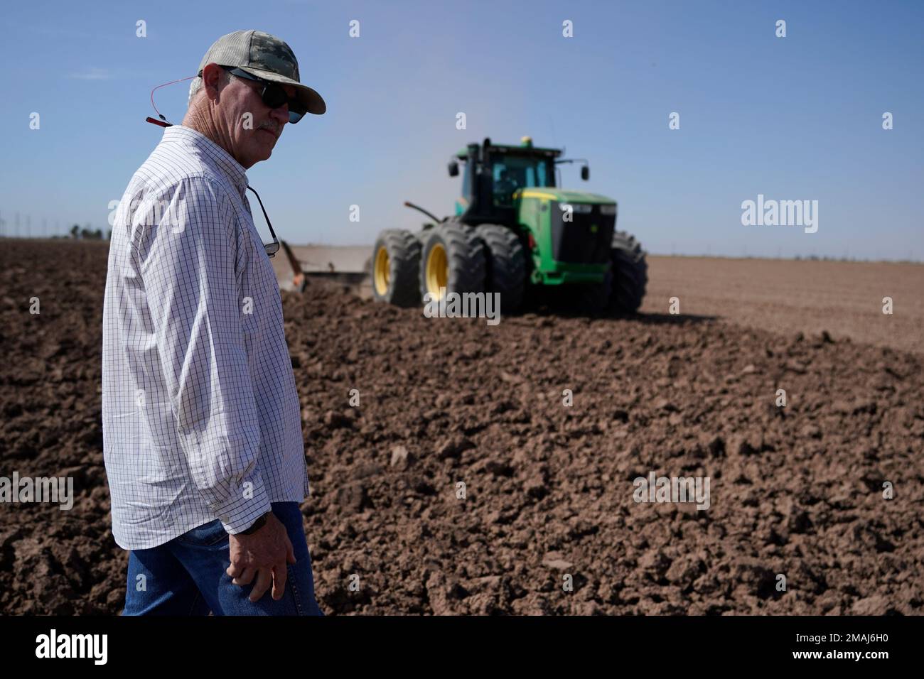 Farmer Larry Cox watches a tractor at work on a field at his farm