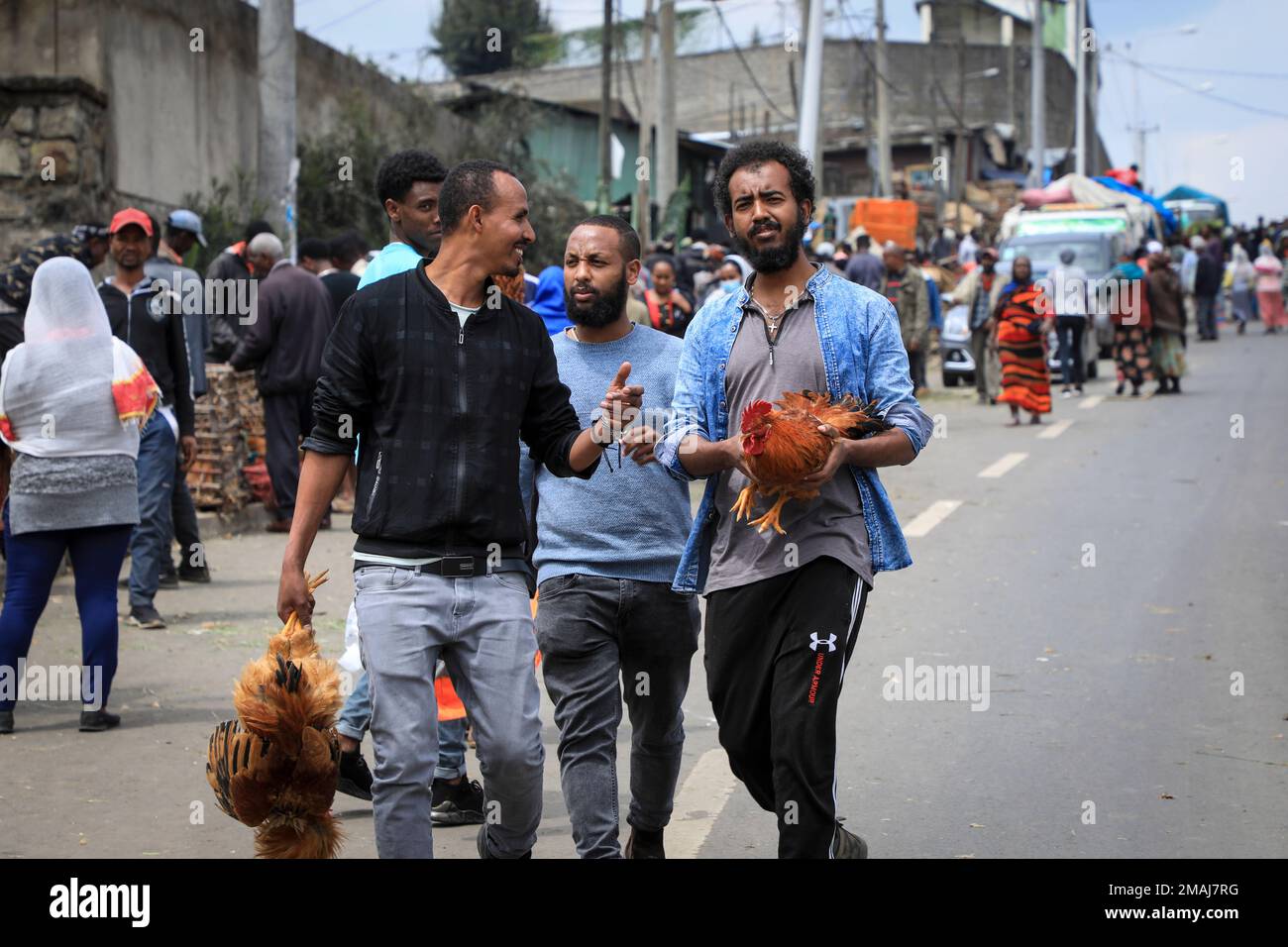 Men carry chickens home after buying them at Sholla Market, the day