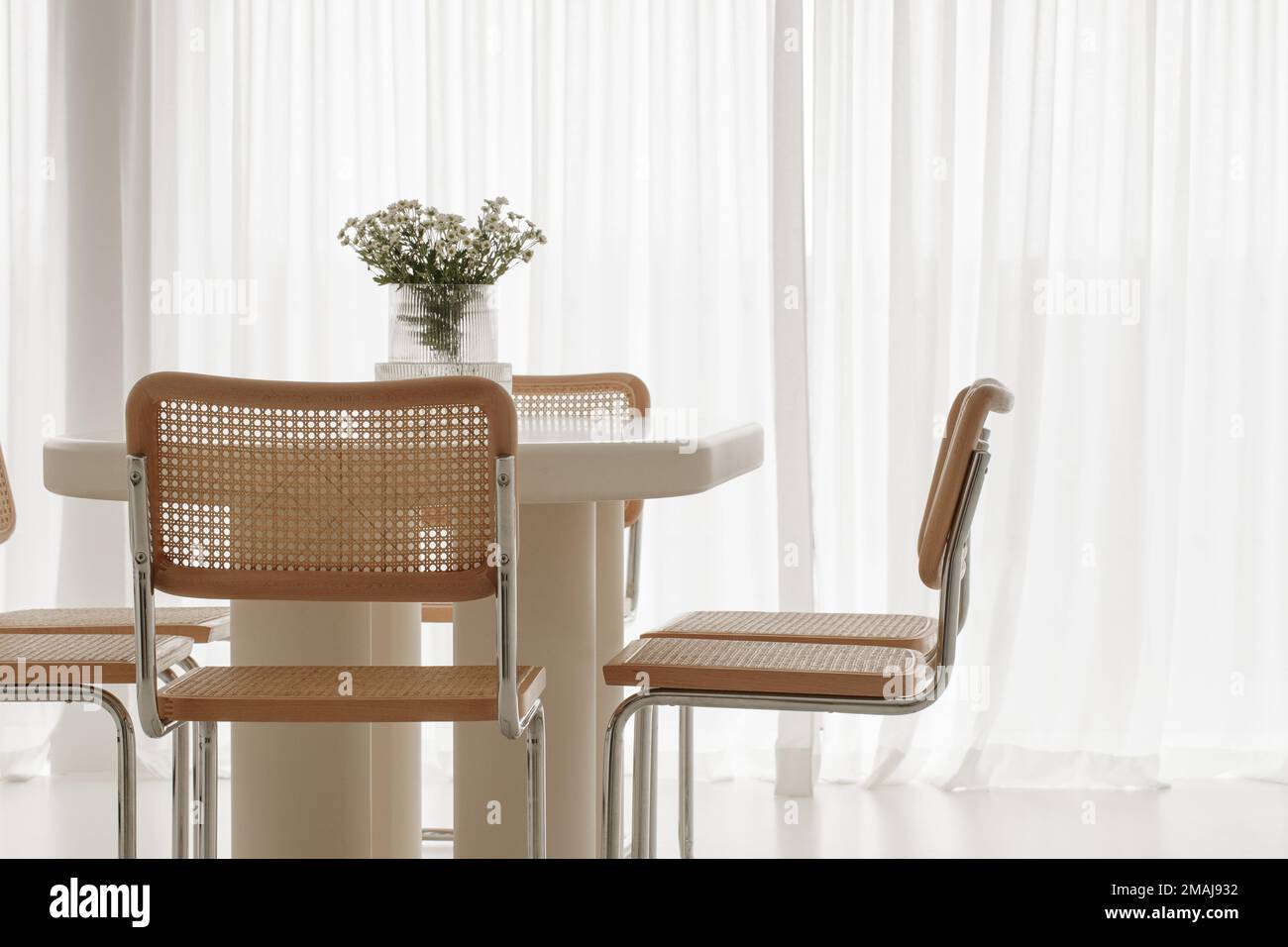 Interior of light dining room with white table, rattan chairs. Japandi interior concept Stock Photo