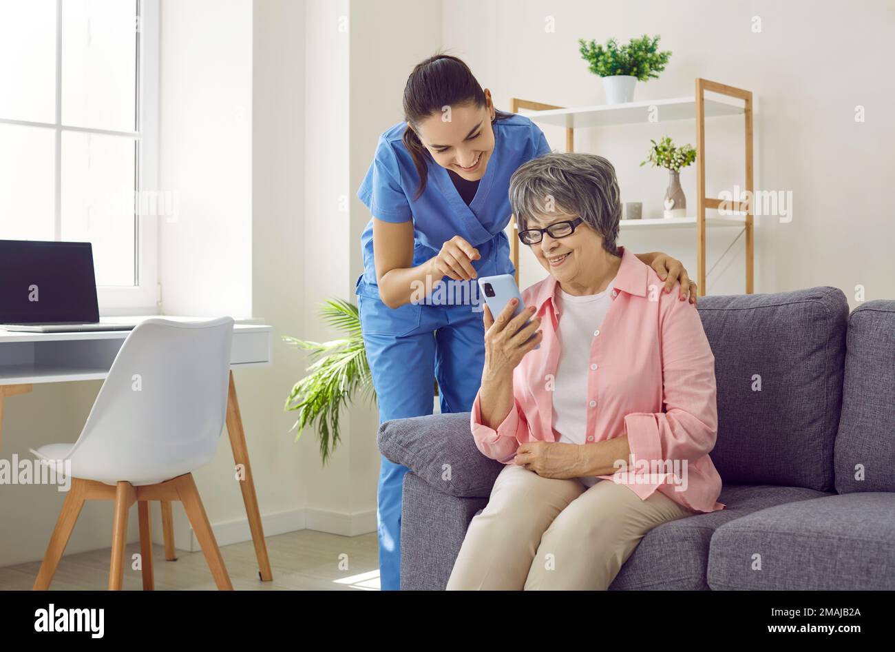 Friendly young nurse teaches older female patient how to download