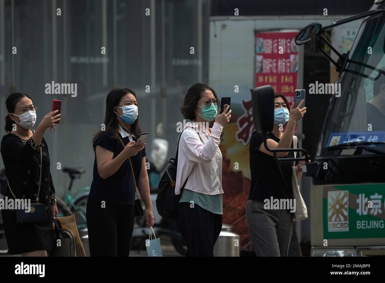 Women wearing face masks use their smartphones to scan health check QR ...