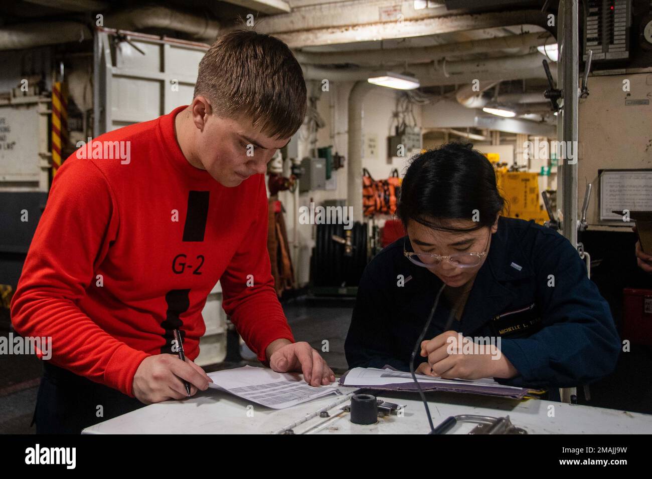 220528-N-GN523-1162 PHILIPPINE SEA (May 28, 2022) Gunner’s Mate 2nd Class Braden McDonald, left, from Colquitt, Georgia and Lt. j.g. Michelle Tran, from Centreville, Virginia perform maintenance in the hangar bay of the U.S. Navy’s only forward-deployed aircraft carrier USS Ronald Reagan (CVN 76). Ronald Reagan Sailors conduct routine maintenance at sea to sustain mission readiness. Ronald Reagan, the flagship of Carrier Strike Group 5, provides a combat-ready force that protects and defends the United States, and supports alliances, partnerships and collective maritime interests in the Indo-P Stock Photo