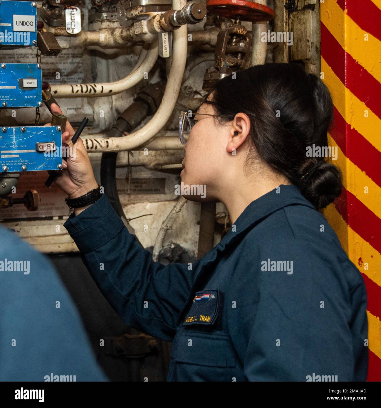 220528-N-GN523-1171 PHILIPPINE SEA (May 28, 2022) Lt. j.g. Michelle Tran, from Centreville, Virginia verifies maintenance performance in the hangar bay of the U.S. Navy’s only forward-deployed aircraft carrier USS Ronald Reagan (CVN 76). Ronald Reagan Sailors conduct routine maintenance at sea to sustain mission readiness. Ronald Reagan, the flagship of Carrier Strike Group 5, provides a combat-ready force that protects and defends the United States, and supports alliances, partnerships and collective maritime interests in the Indo-Pacific region. Stock Photo