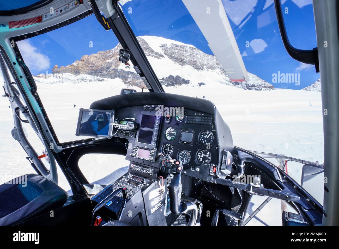 Helicopter cockpit inside, on ground snow. Close up of instruments, look out to snow covert mountains. Jungfrau Joch, Grindelwald Switzerland Stock Photo