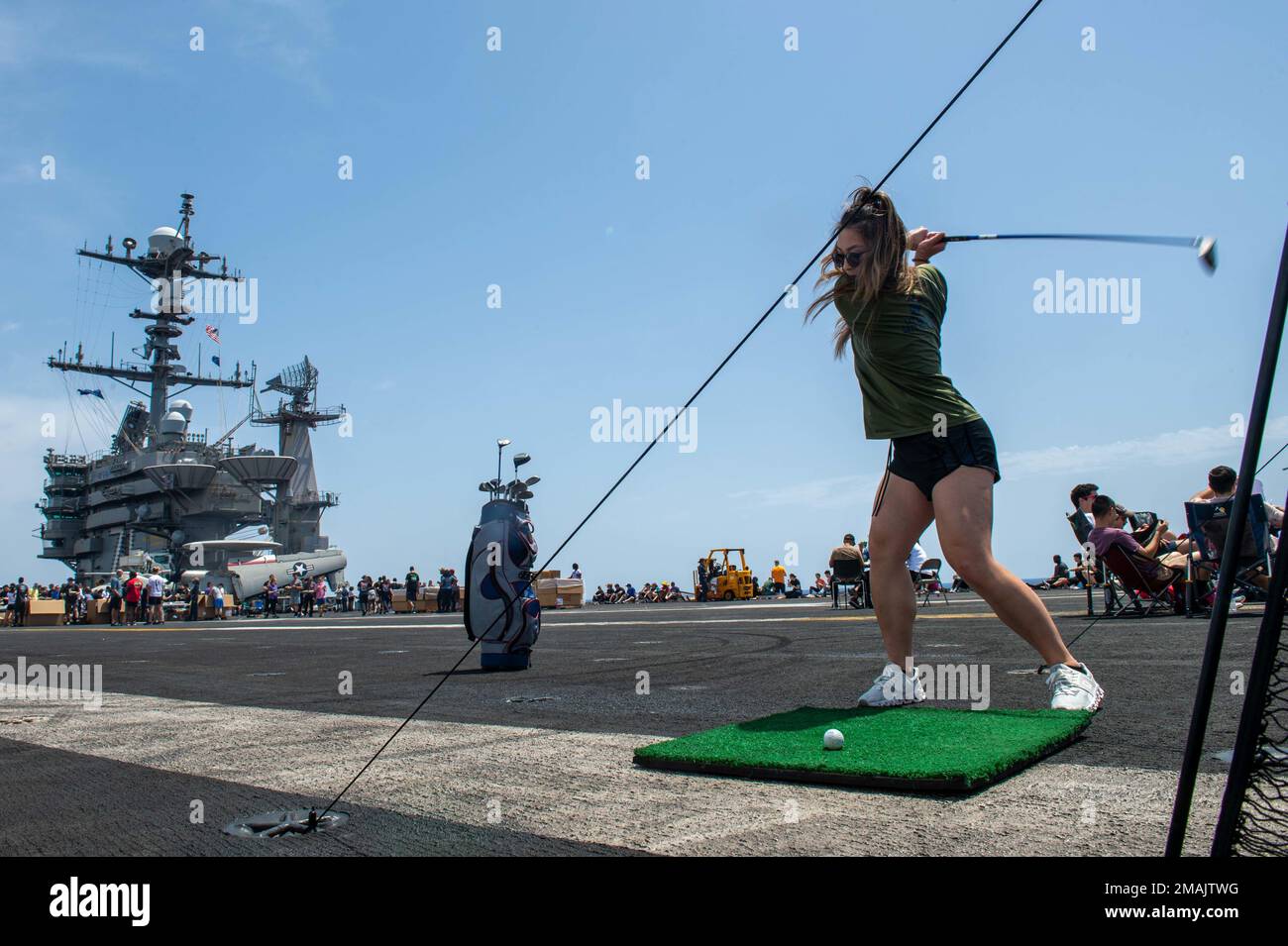 220528-N-GP384-1053 ADRIATIC SEA (May 28, 2022) Lt. j.g. Steffi Yo, from Tampa, Florida, swings a golf club on the flight deck of USS Harry S. Truman (CVN 75), during a steel beach picnic, May 28, 2022. The Harry S. Truman Carrier Strike Group is on a scheduled deployment in the U.S. Naval Forces Europe area of operations, employed by U.S. Sixth Fleet to defend U.S., Allied and Partner interests. Stock Photo