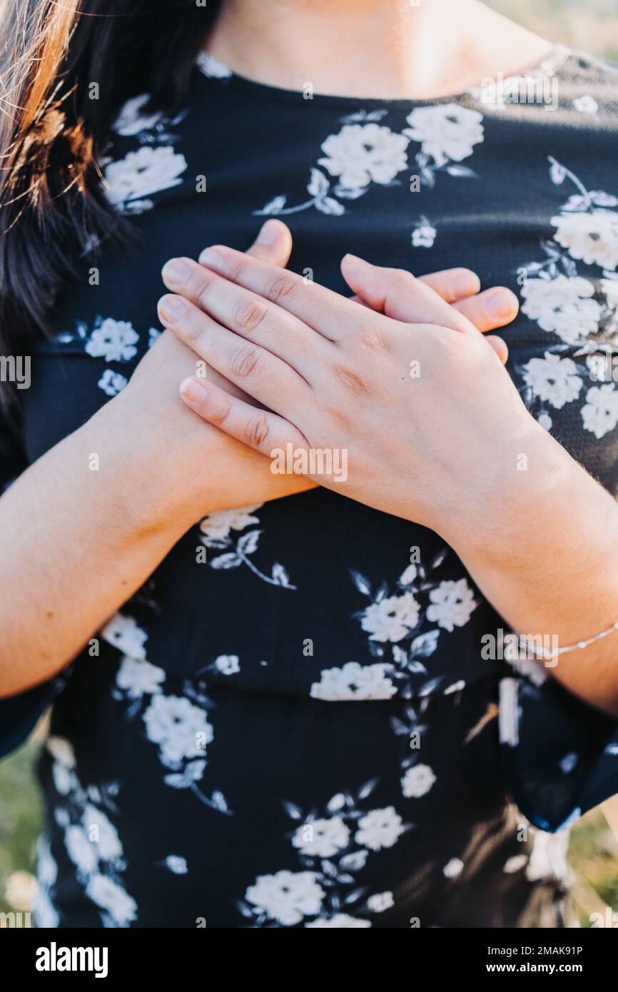Hopeful woman putting hands on her heart in gratitude for God's blessings, in the field. Copy space Stock Photo